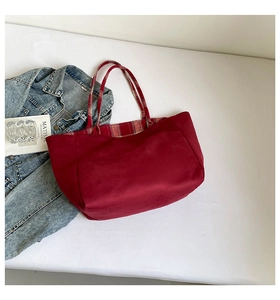 Detailed flat lay of deep red tote bag featuring vibrant plaid interior and handle lining