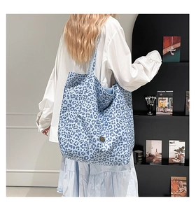 Close-up of blue leopard print tote bag with feline pattern and canvas texture