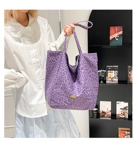 Detail of purple leopard print canvas tote bag with gold logo on a large capacity bag