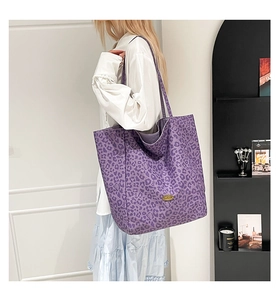 Detail view of large purple leopard print tote bag with metallic logo plate detail
