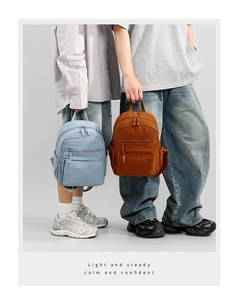 Detail of blue and brown nylon backpacks featuring multiple zipper pockets and top handle