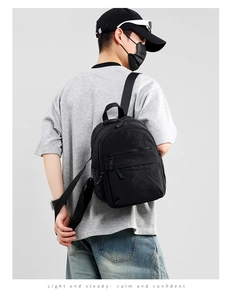 Lightweight black nylon backpack for men shown on model for size and scale reference