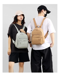 Detail view of light grey and khaki nylon backpacks on models showing storage compartments
