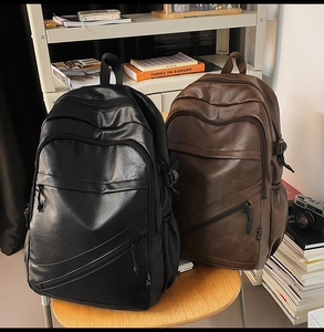 Detail shot of vintage PU leather backpacks in black and brown on a rustic wooden stool