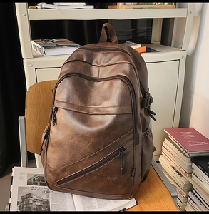 Detail of dark brown leather laptop backpack showing textured finish and functional pockets