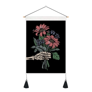 Macro detail of skull hand holding flowers tapestry with wooden rod and black tassels