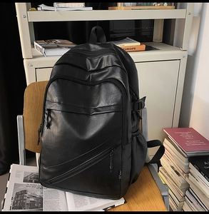 Detail of black PU leather business backpack on a wooden chair with library background