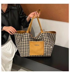 Detail of a large checkered tote bag with a yellow pocket shown on a female model