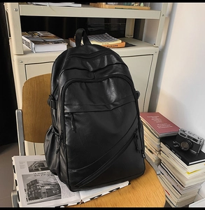Detail of black leather laptop backpack featuring multi-zipper pockets for business travel