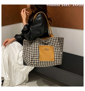 Close-up of checkered canvas tote bag with front pocket and brand logo detail