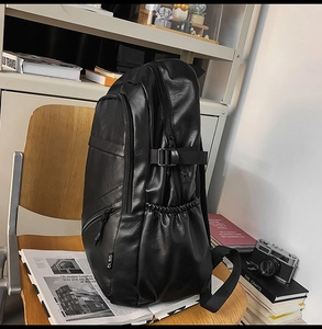 Detail view of black leather backpack side pocket with zipper and adjustable buckle strap