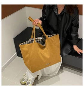 Detail of yellow tote bag featuring contrast checkered lining and small metal plaque
