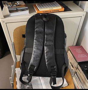 Detail of breathable mesh back panel and padded straps on a black leather business backpack