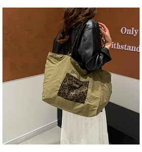 Detail of olive green nylon tote bag featuring leopard print pocket and gold logo