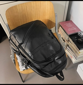Detail of black leather laptop backpack with zipper pocket on a wooden chair