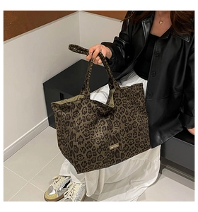 Detail view of the leopard print canvas tote bag featuring a stitched 'our fave' logo label