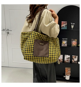 Close-up of a yellow and black plaid canvas tote bag with a dark brown front pocket