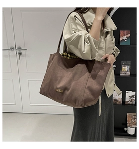 Close-up of brown suede tote bag featuring our fave metal logo and plaid inner lining