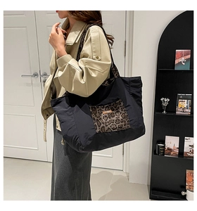 Detail of black canvas tote bag with leopard print pocket and our love label