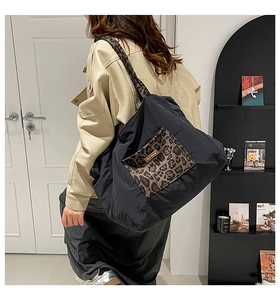 Detail of black tote bag featuring leopard print pocket and wide shoulder strap style