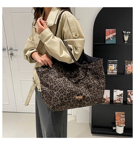 Macro detail of leopard print canvas tote bag with brown leather label on shoulder strap