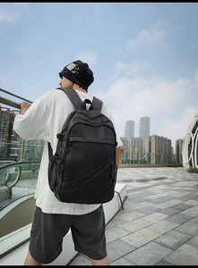 Outdoor shot of a man wearing a black faux leather laptop backpack with a sleek matte finish