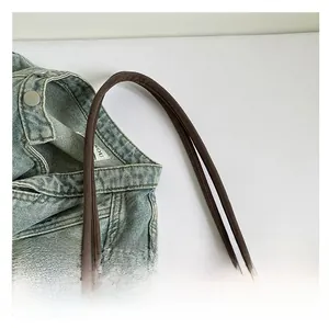 Detail of reinforced canvas handle and stitching on dark brown tote bag