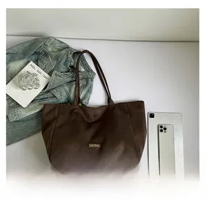 Macro shot of dark brown suede tote bag with metal logo and long shoulder handles