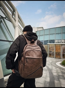 Outdoor shot showing the brown vintage PU leather backpack with multi-pocket design on model