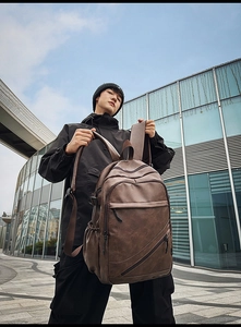 Detail of dark brown leather travel backpack with multiple zippers and wide straps