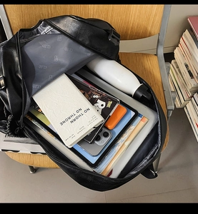 Top view of large black leather backpack showing interior storage for a laptop and books