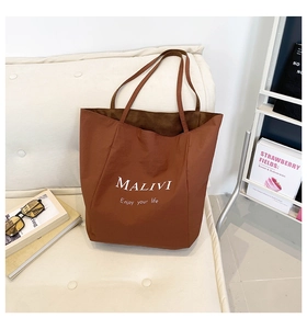 Detailed close-up of brown tote bag with white MALIVI brand text on a soft white sofa