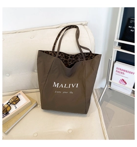 Detail view of large brown tote bag showing leopard print lining and white text