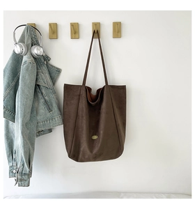 Detailed texture of brown matte tote bag hanging on wooden hook with casual style accessories