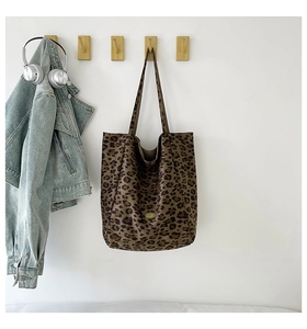 Close-up of leopard print canvas tote bag hanging on a wooden hook with stylish accessories