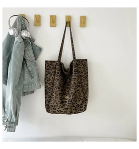 Detailed close-up of leopard print tote bag hanging with denim jacket and headphones