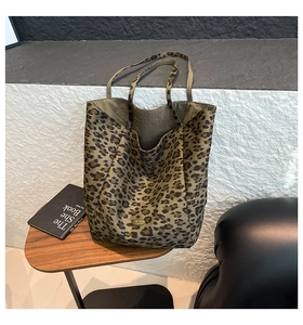 Detail of leopard print tote bag featuring a metallic logo and soft fabric texture