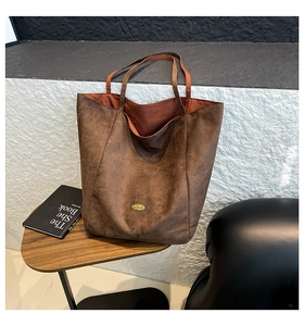 Close-up of vintage brown tote bag with metal plaque on rustic wooden table