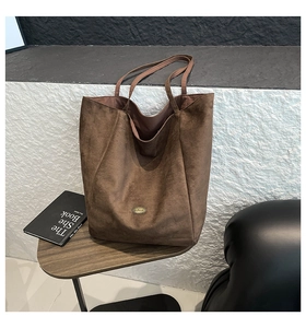Close-up of deep brown suede tote bag featuring matte texture and metal emblem