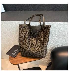Detail of classic leopard print tote bag with golden metal logo plaque on a wooden table