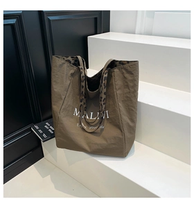 Detail of brown nylon tote bag with leopard print lining and white letter branding