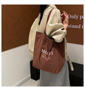 Close-up of brown tote bag with MALI lettering on textured waterproof fabric