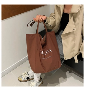 Detail shot of a brown tote bag with white MALIVI print and stylish star motif sneakers