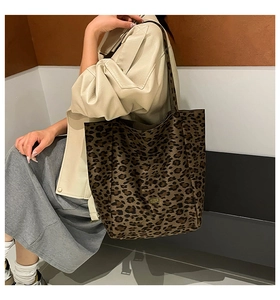 Detailed shot of a large leopard print tote bag with metal logo on a shoulder strap