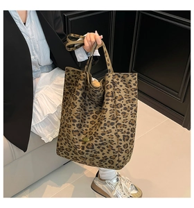 Detailed macro view of the leopard print pattern and handmade metal tag on a canvas tote bag