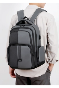 Détail montrant le port de charge USB et le design multi-compartiments du sac à dos gris
