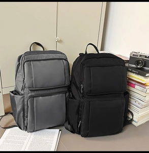 Close-up of minimalist business backpacks in grey and black with multi-pocket storage design