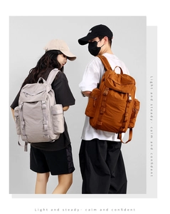 Detail of 25L outdoor backpacks showing large zipper side pockets and buckled flap closure