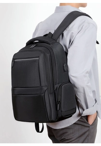 Close-up of black business backpack side showing external USB charging port and nylon texture