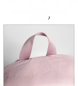Detail of the light pink nylon backpack showing a sturdy reinforced webbing carry handle